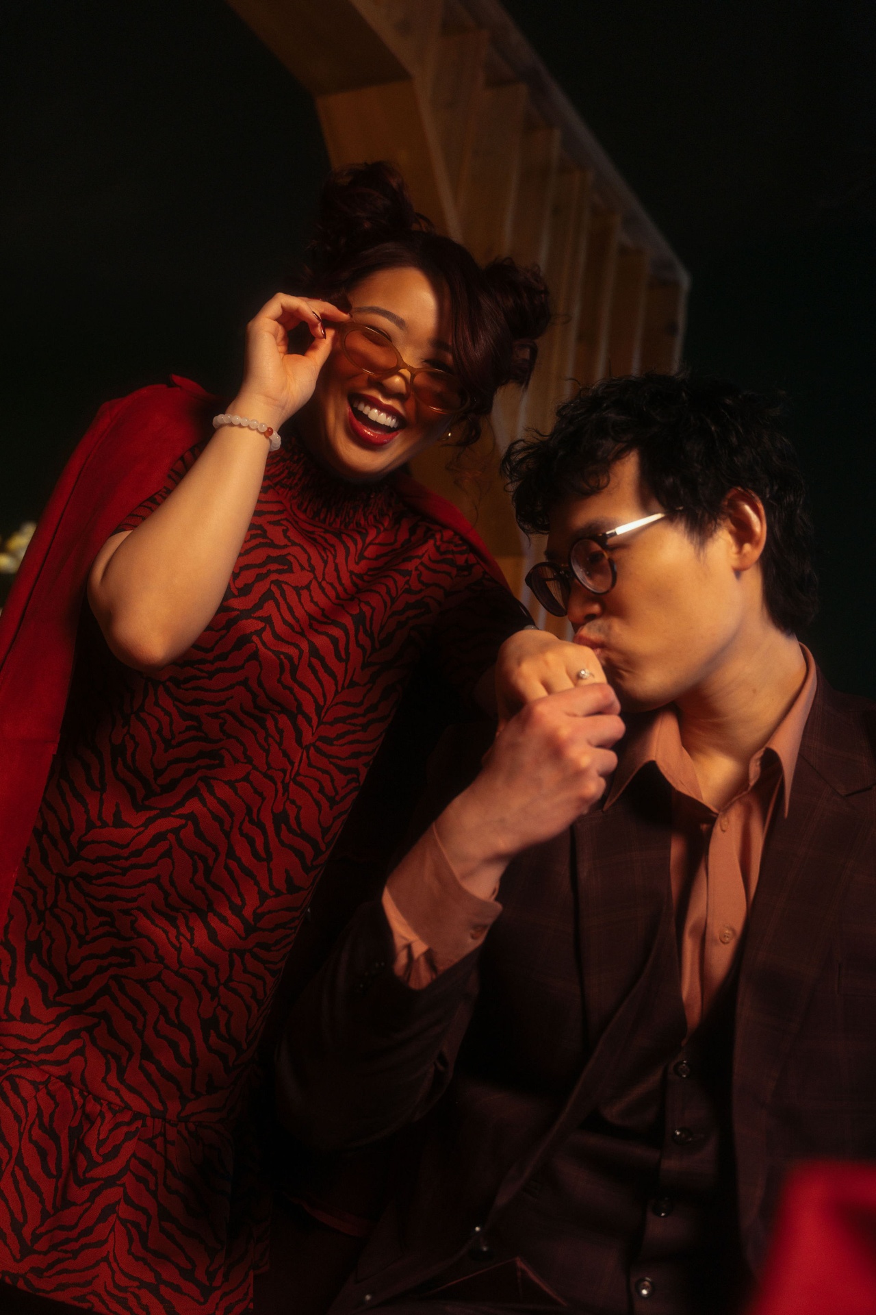 Teck Yan kissing Julie's hand while she laughs in tinted glasses